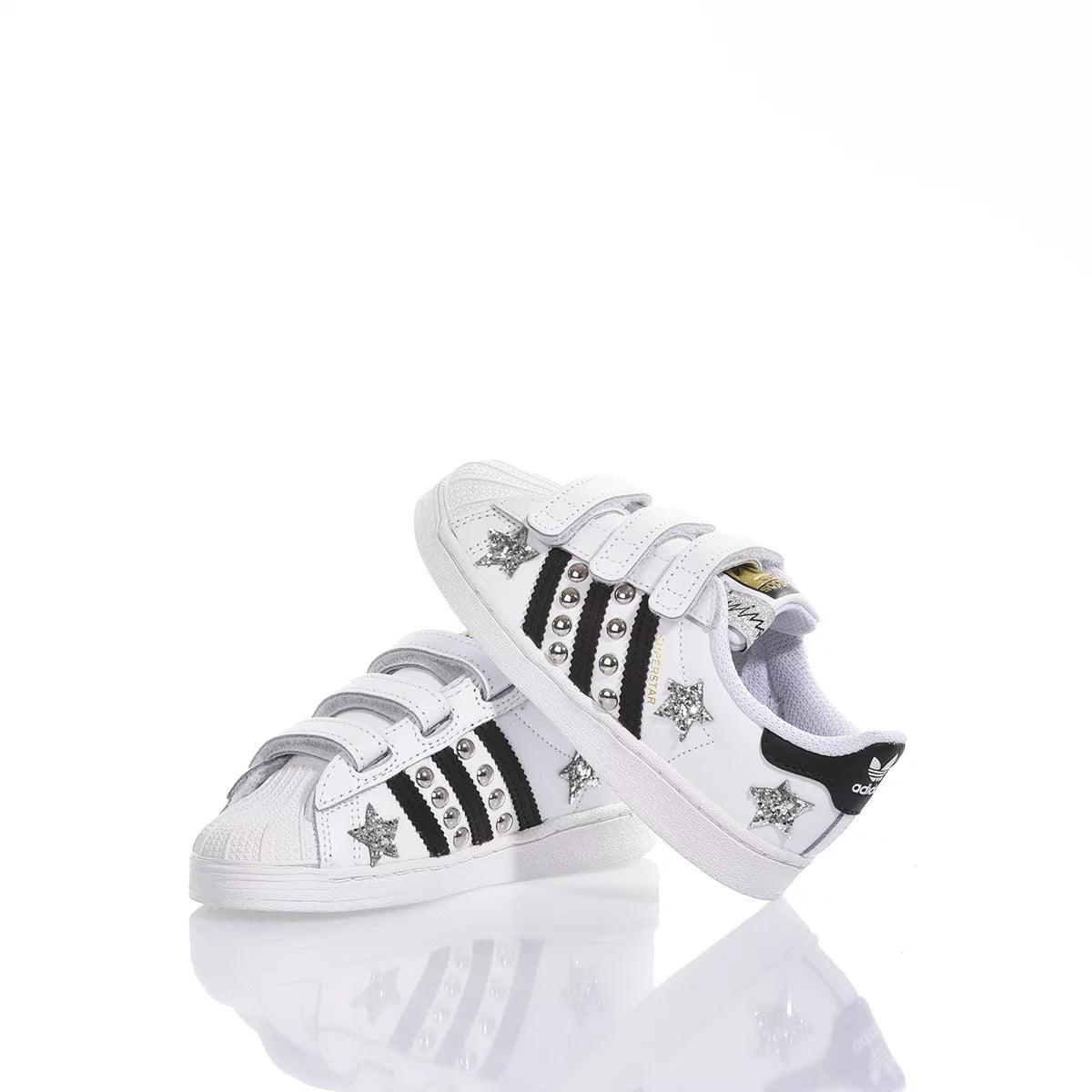Scarpe da bambino bianche con stelle glitter e strisce nere, chiusura a strappo.