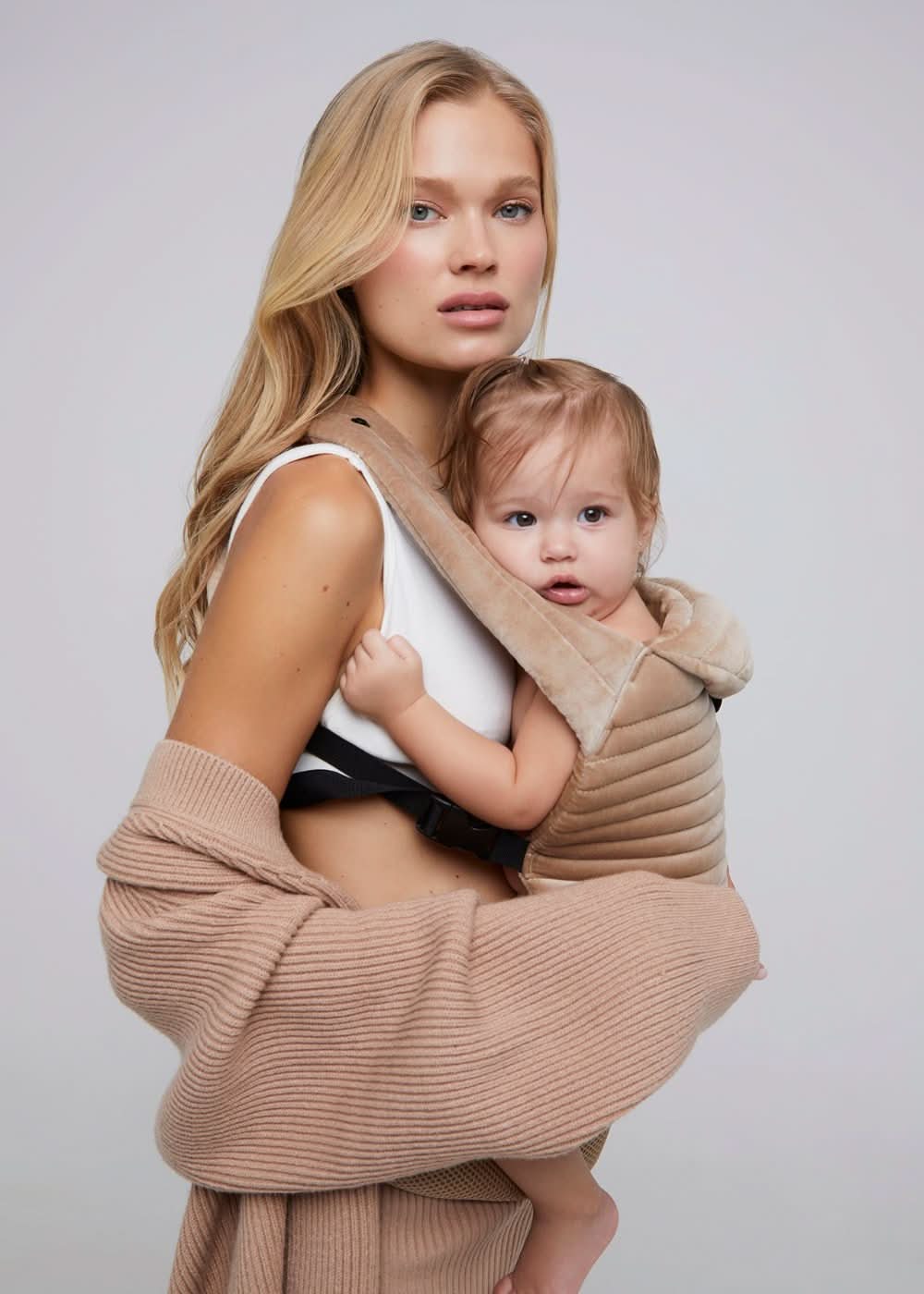 Mamma con abbigliamento premaman beige e marsupio porta bebè elegante