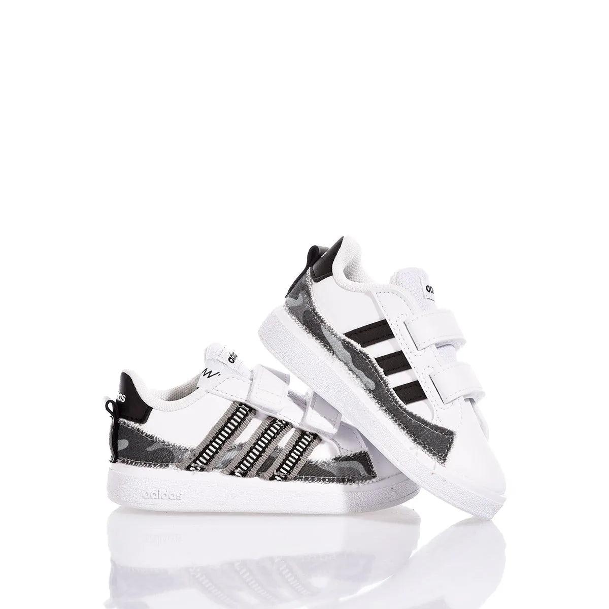 Scarpe sportive bianche per bambini con strisce nere, ideali per outfit premaman.
