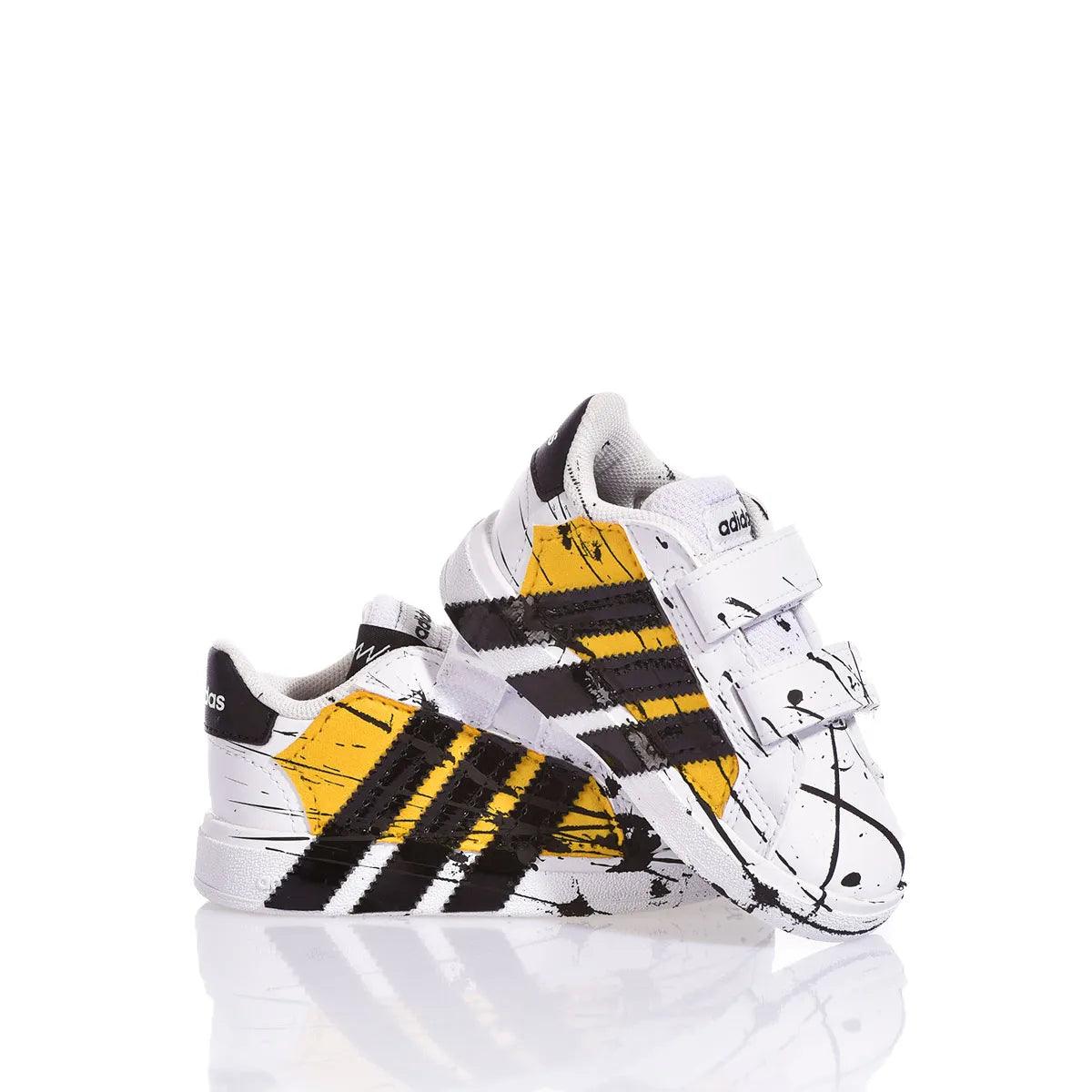 Sneakers bianche da bambino con dettagli neri e gialli, chiusura in velcro, stile sportivo