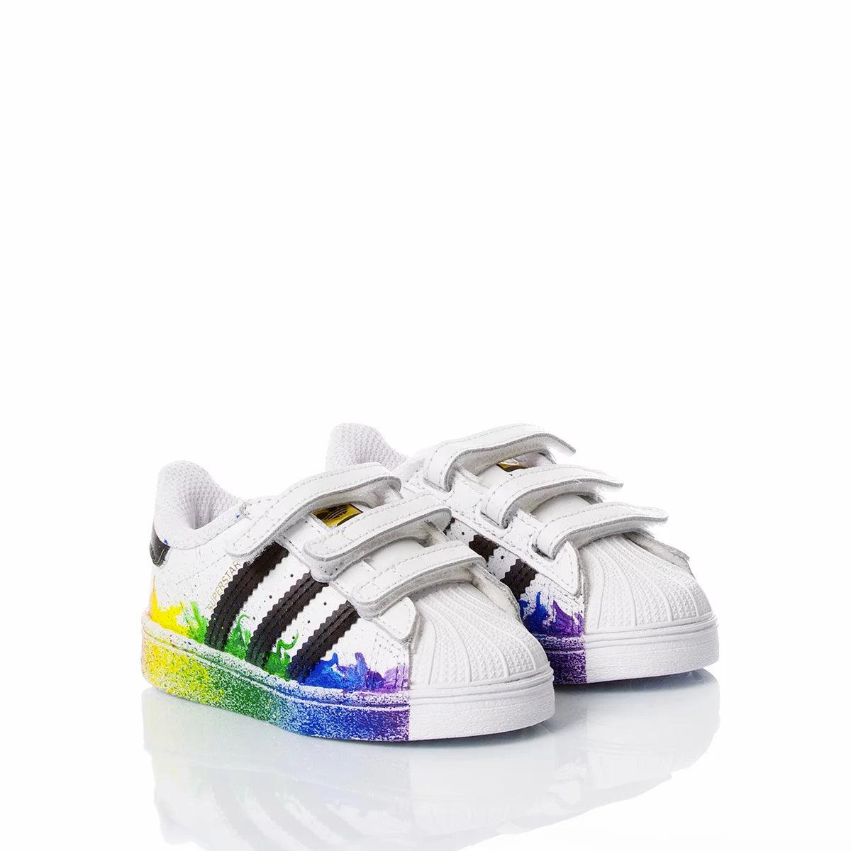 Scarpe bianche bambino con strisce nere e dettaglio arcobaleno, adatte per look premaman casual.