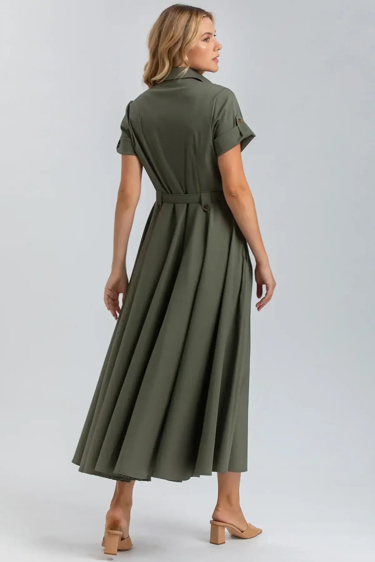 Donna di profilo indossa abito premaman verde lungo, maniche corte, sandali beige