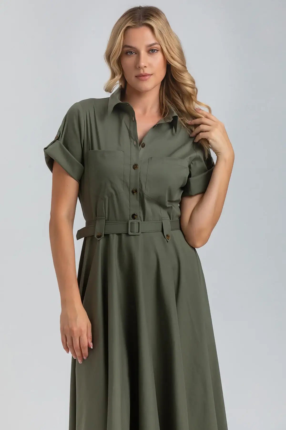 Abito premaman verde oliva con cintura, maniche risvoltate e bottoni, indossato da donna bionda.