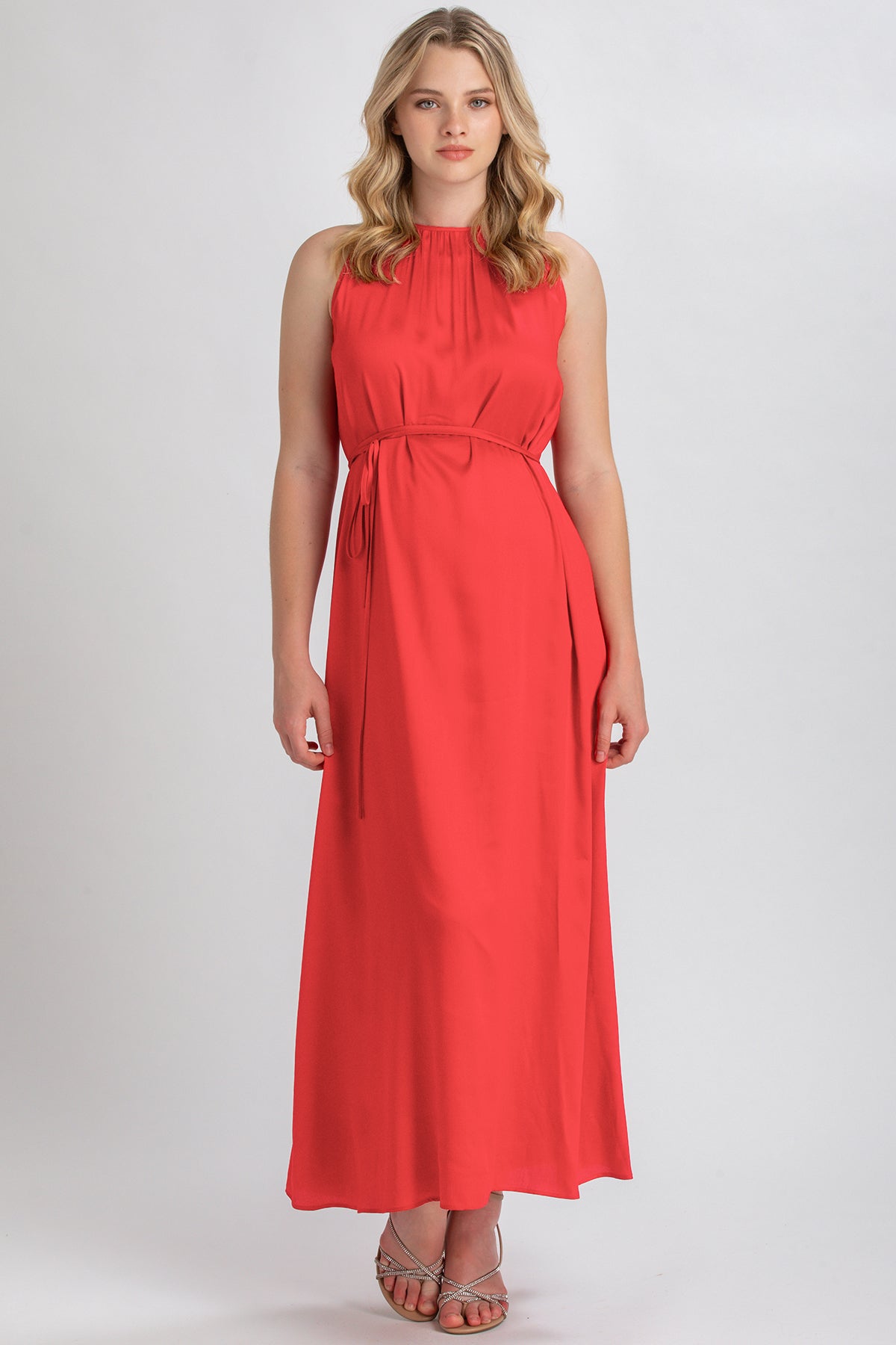 Abito premaman lungo rosso senza maniche, elegante, con cintura in vita, su sfondo neutro.