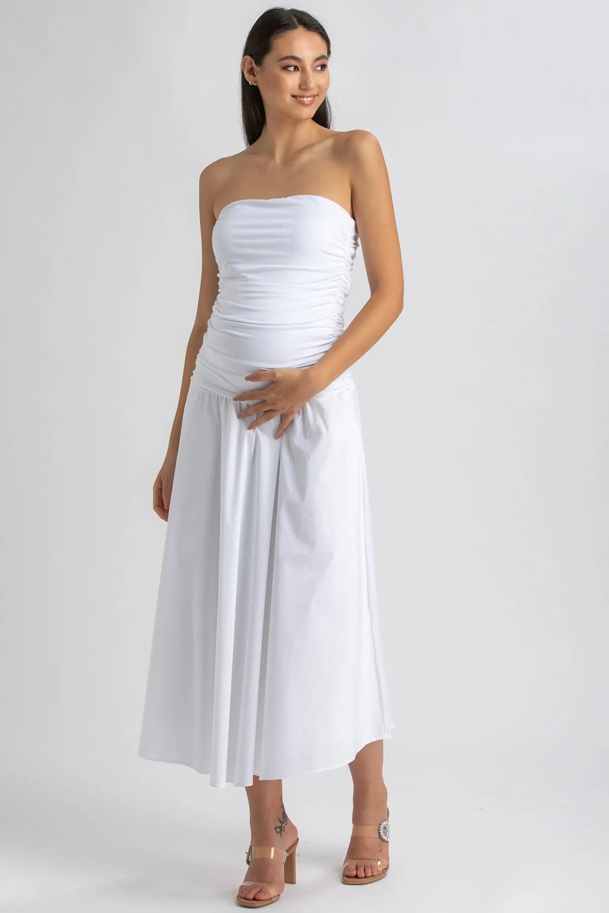 Donna incinta con abito premaman bianco senza spalline, tessuto morbido, stile elegante