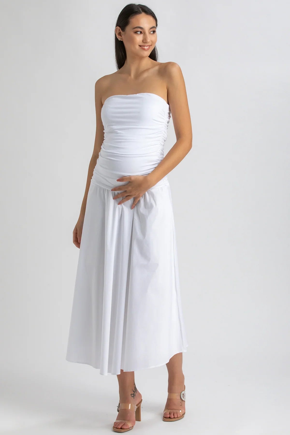 Donna incinta con abito premaman bianco senza spalline, tessuto morbido, stile elegante