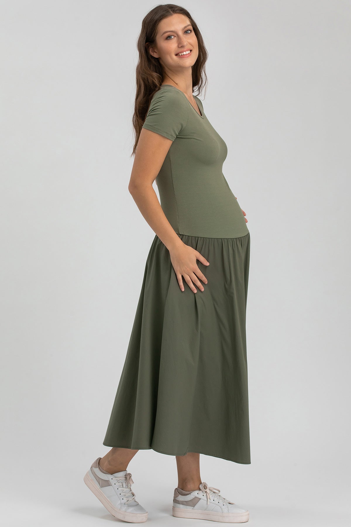 Vestito premaman verde militare a maniche corte, lungo e comodo, indossato da una donna sorridente.