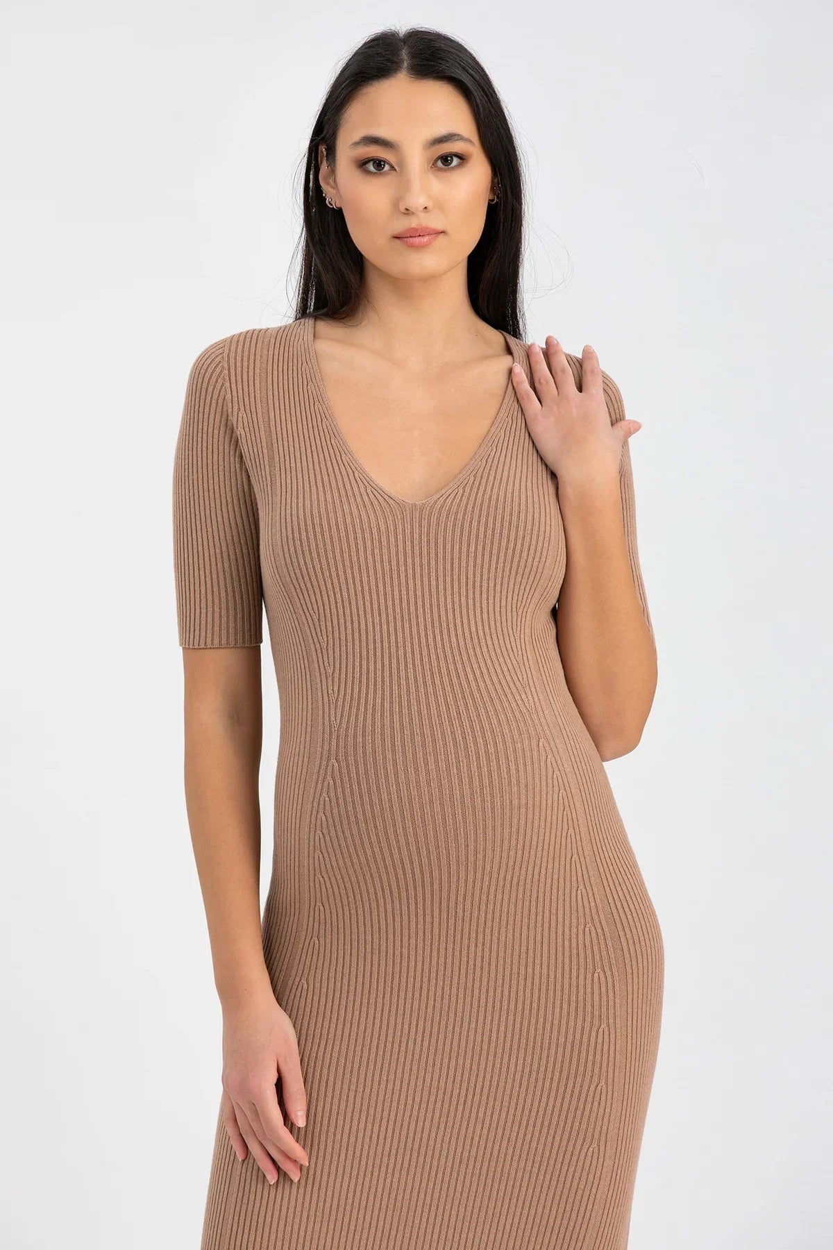 Modella con abito premaman in maglia beige a costine e scollo a V, fondo neutro