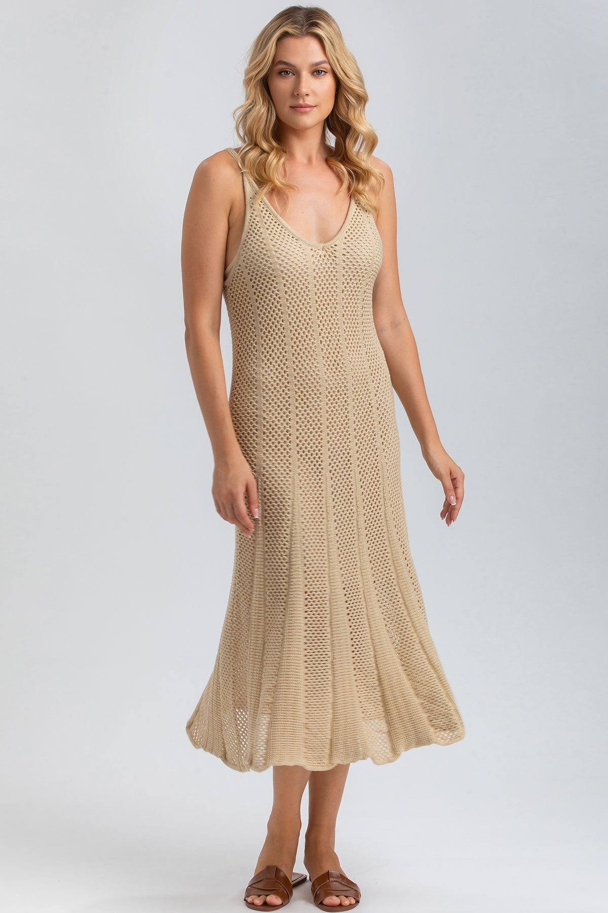 Donna con abito premaman beige traforato, senza maniche, su sfondo neutro.
