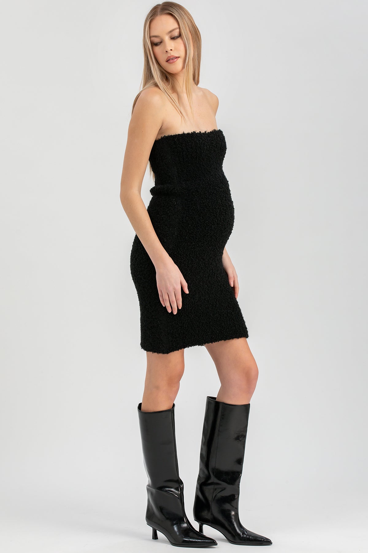 Donna in abito nero senza spalline e stivali alti neri, moda elegante premaman