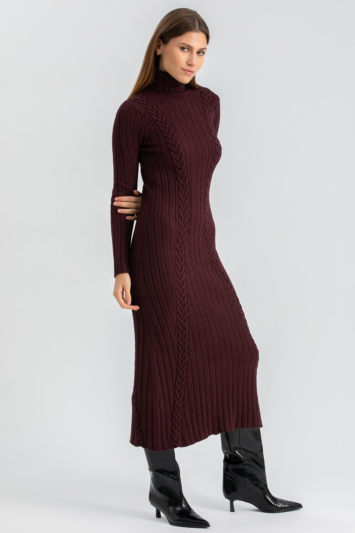 Abito premaman lungo bordeaux a coste con collo alto e stivali neri, donna in posa elegante