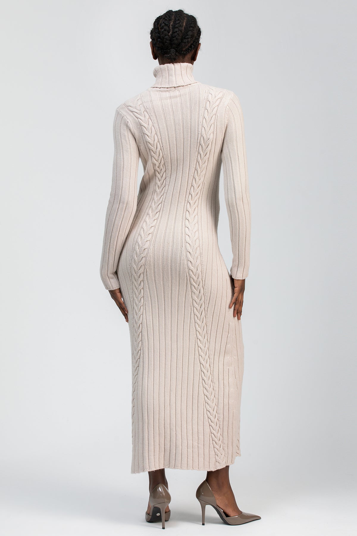 Abito premaman lungo in maglia beige, collo alto, lavorazione a trecce, indossato da donna.