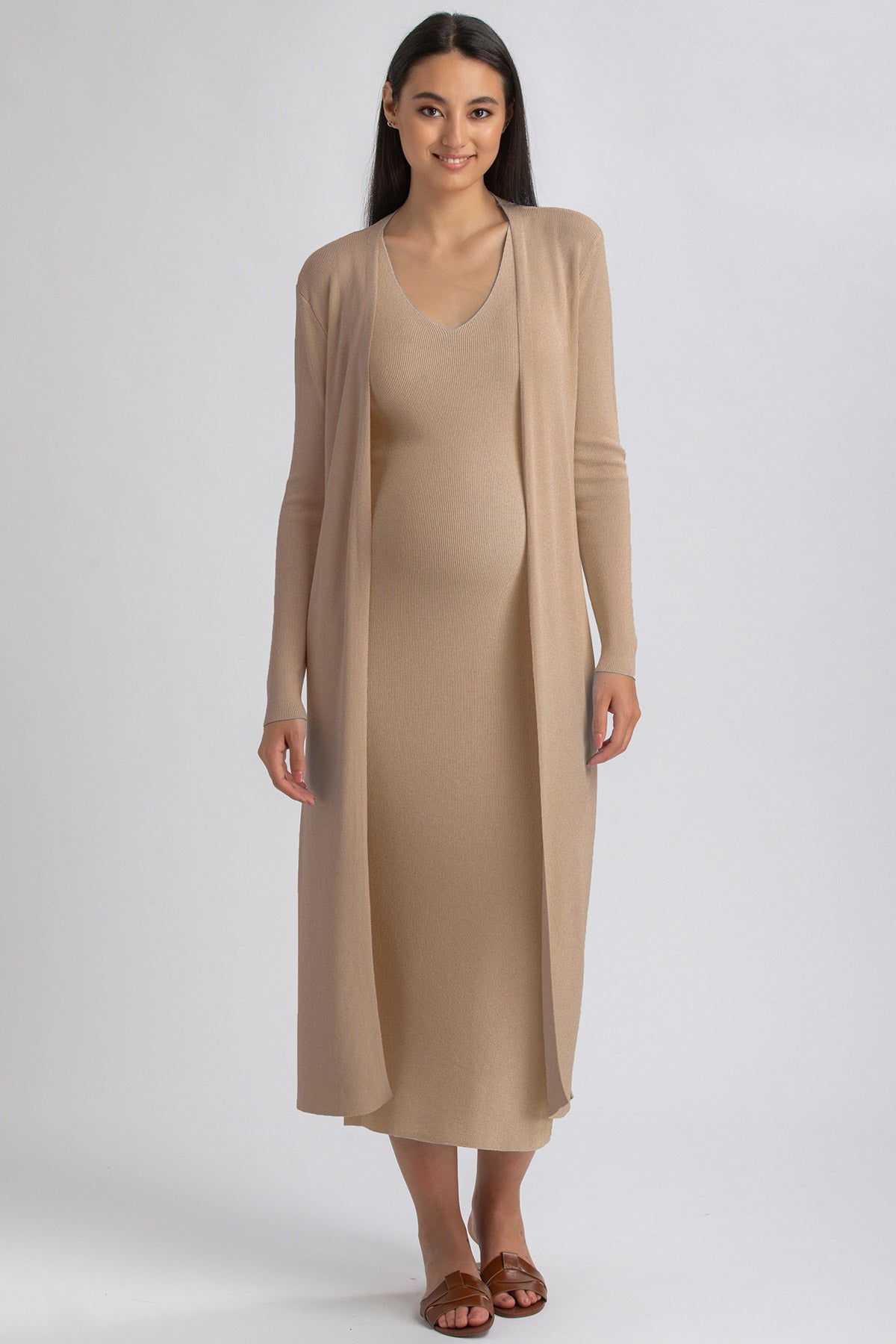 Modella con abito premaman beige lungo e cardigan coordinato, moda maternità elegante.