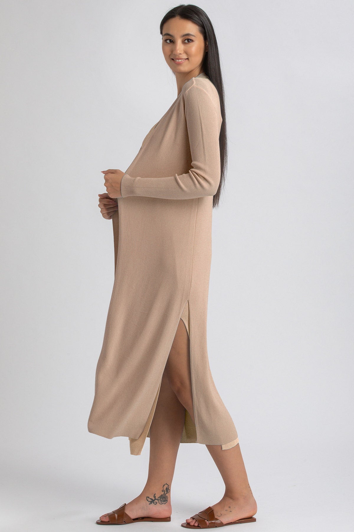 Donna incinta con abito premaman beige a maniche lunghe e spacco laterale