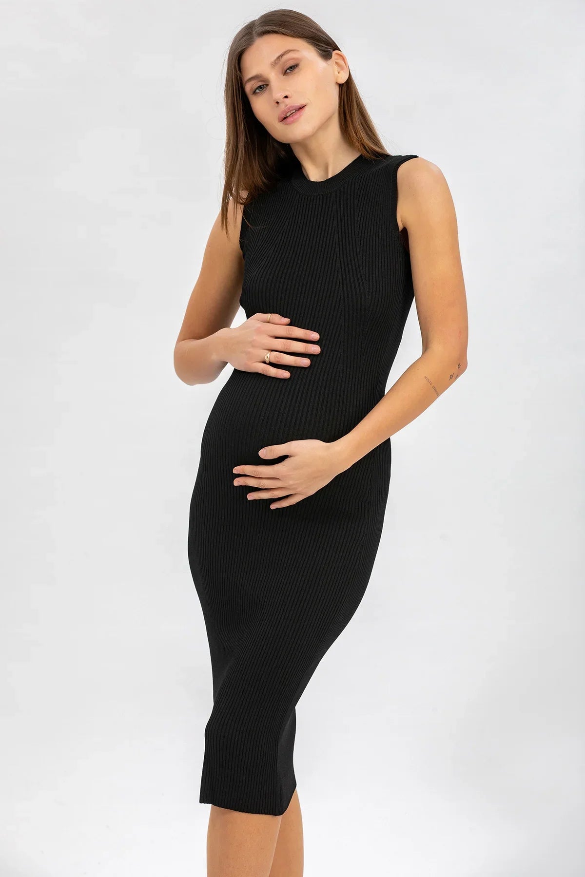 Donna incinta con abito premaman nero senza maniche in maglia, sfondo neutro
