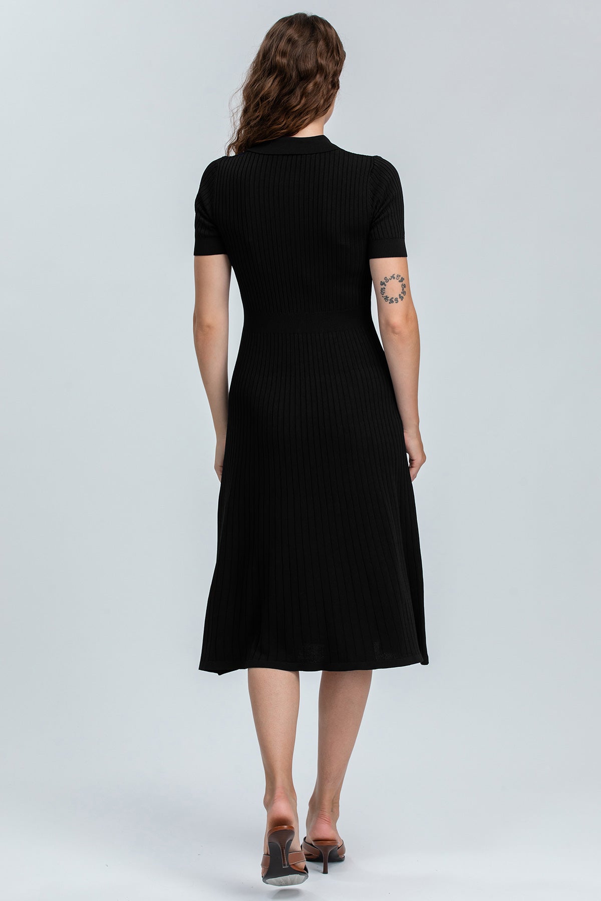 Donna di spalle con abito premaman nero a costine, maniche corte, look elegante