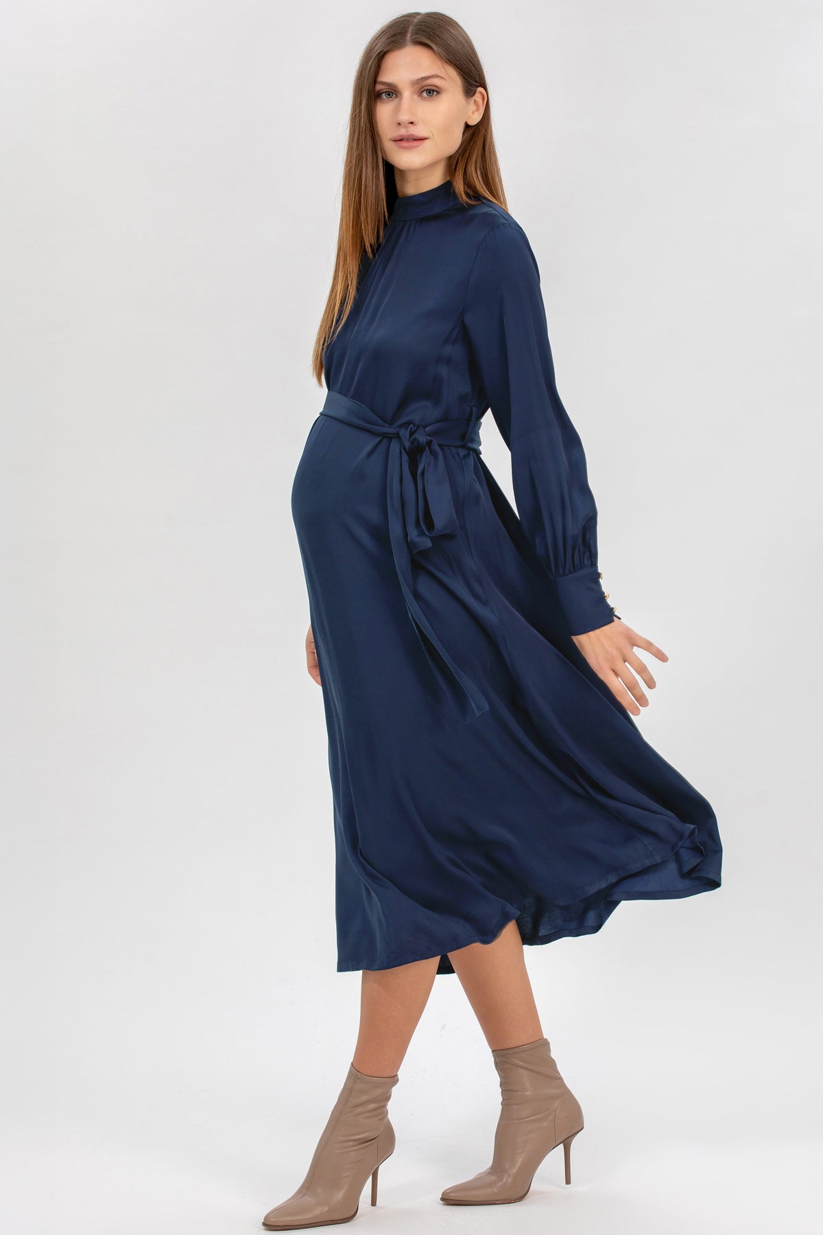 Abito premaman elegante blu a maniche lunghe in tessuto fluido, indossato da donna incinta.