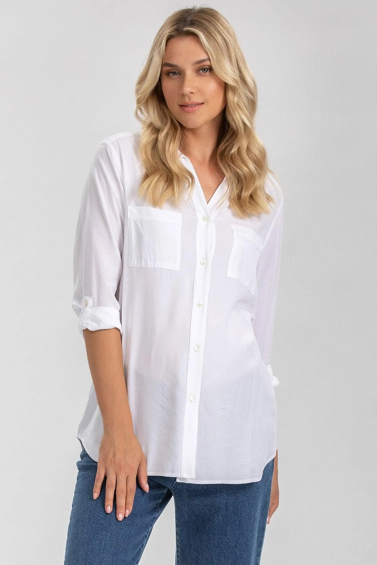 Camicia premaman bianca a maniche lunghe, tessuto leggero, indossata da donna in jeans