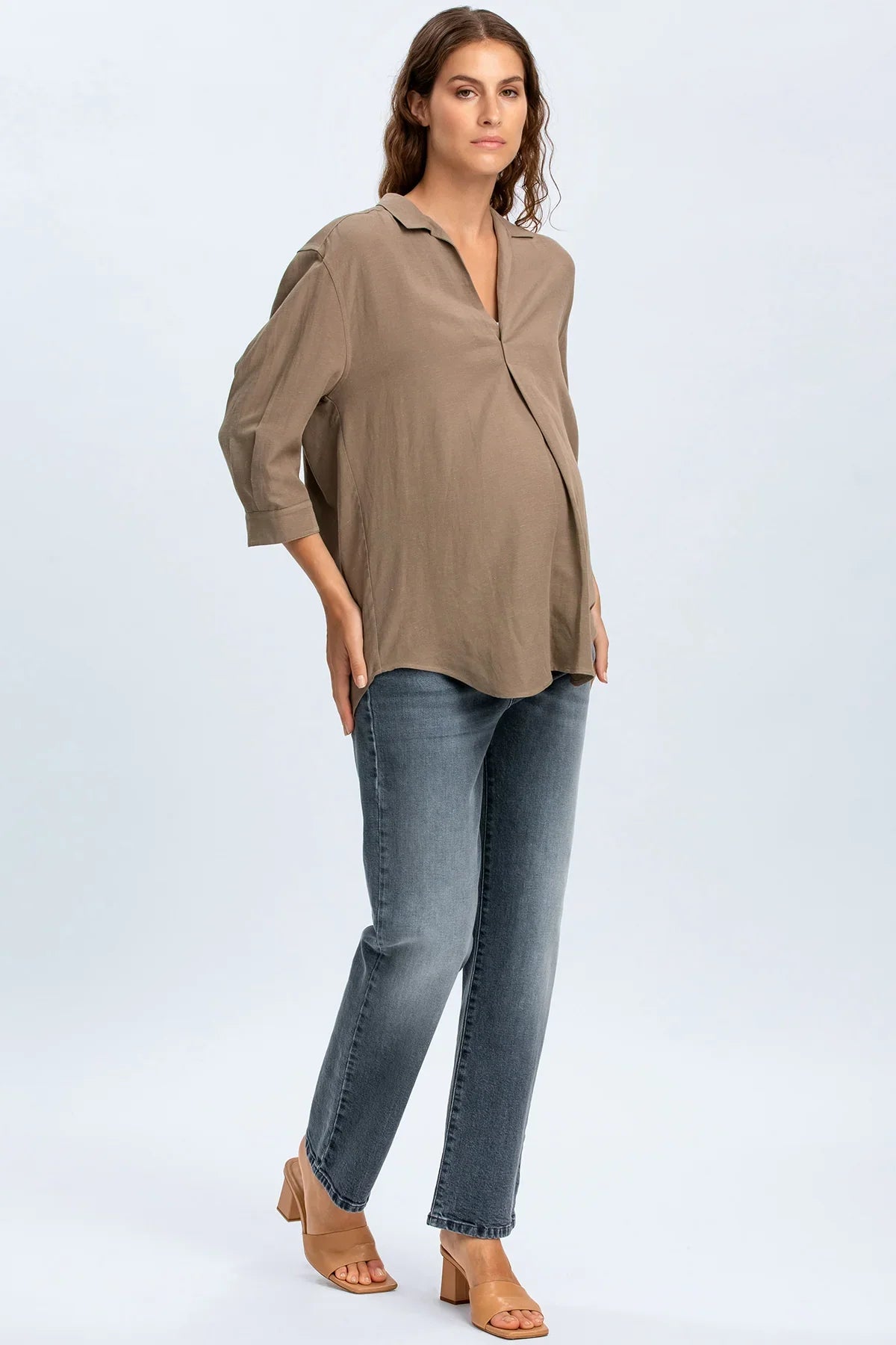 Modella indossa camicia premaman beige e jeans premaman dritti, look casual elegante