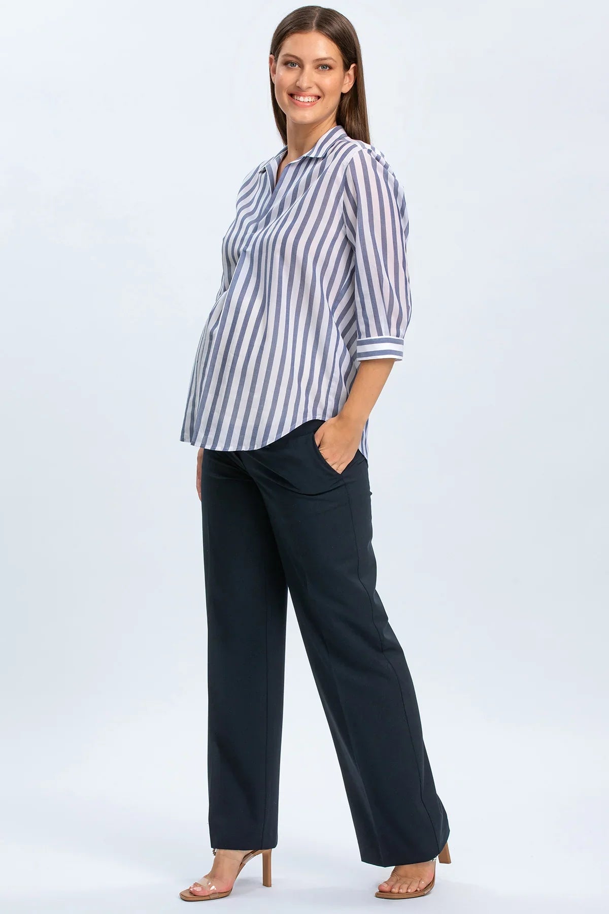 Donna incinta con camicia premaman a righe blu e pantaloni eleganti premaman.