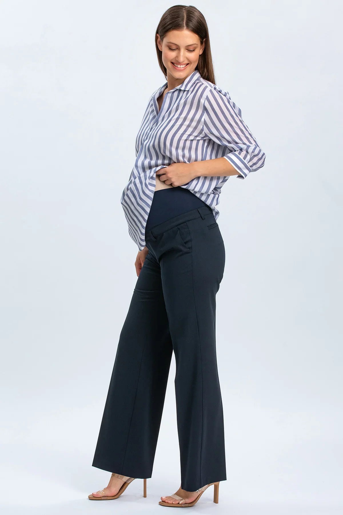 Donna incinta con camicia a righe e pantaloni premaman eleganti blu scuro