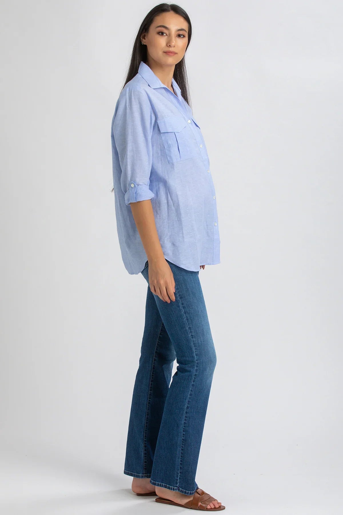 Donna incinta con camicia premaman azzurra e jeans flare, look casual elegante
