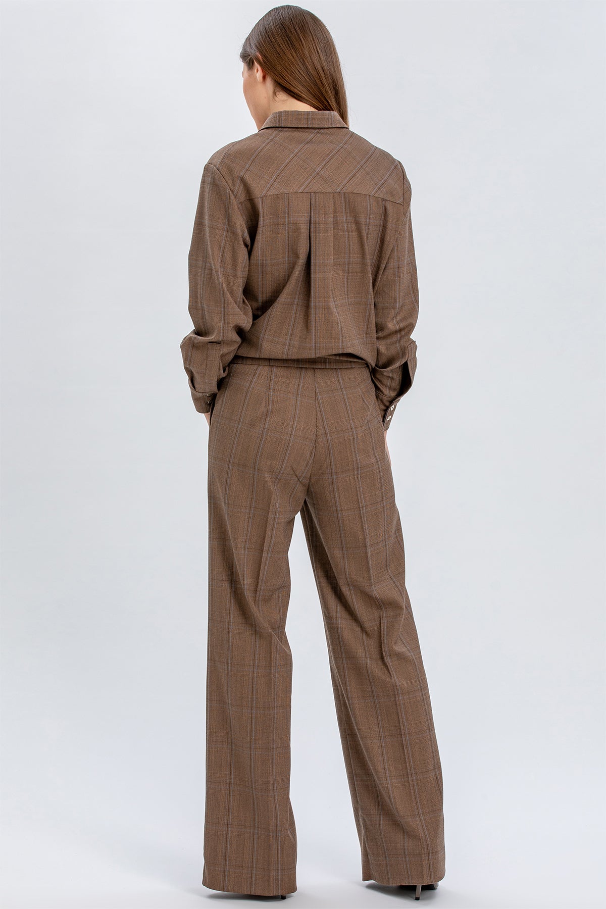 Donna di spalle con completo premaman marrone a quadri, pantaloni larghi eleganti