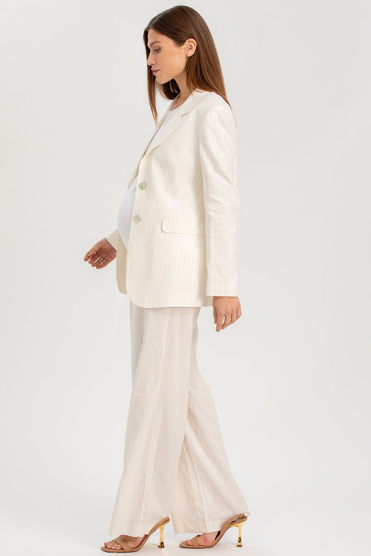 Donna incinta con completo premaman elegante avorio, giacca e pantaloni larghi