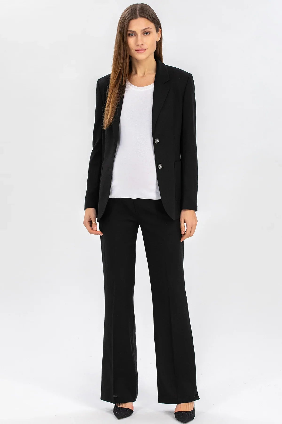 Completo premaman donna elegante con giacca e pantaloni neri, top bianco, su sfondo neutro