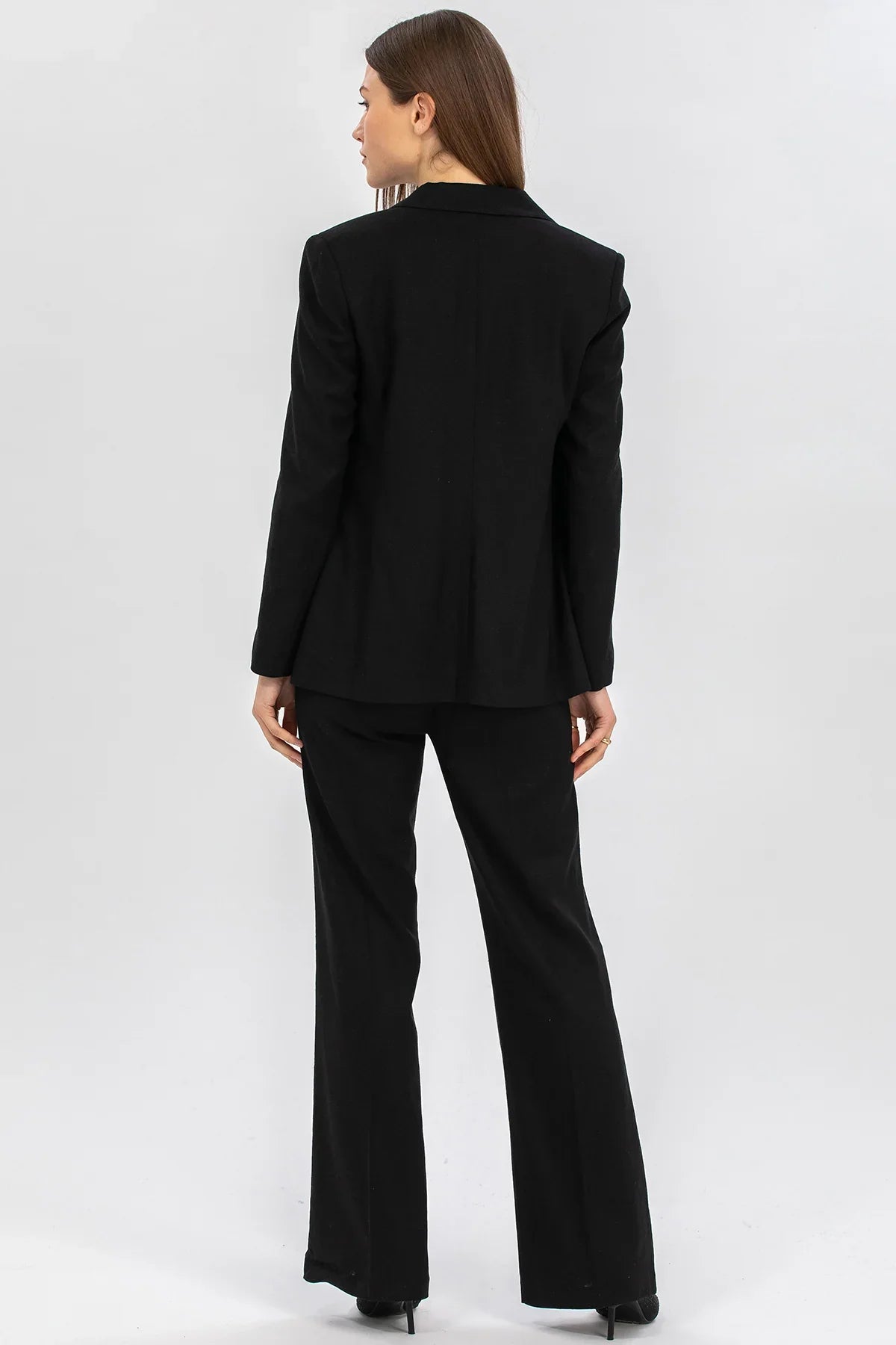 Donna in tailleur premaman nero elegante vista posteriore su sfondo neutro
