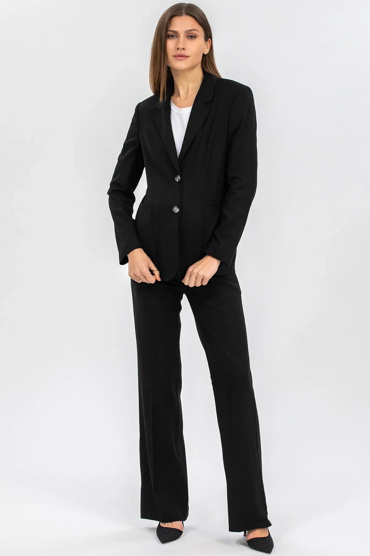 Donna incinta con completo premaman nero elegante, giacca e pantaloni, sfondo bianco