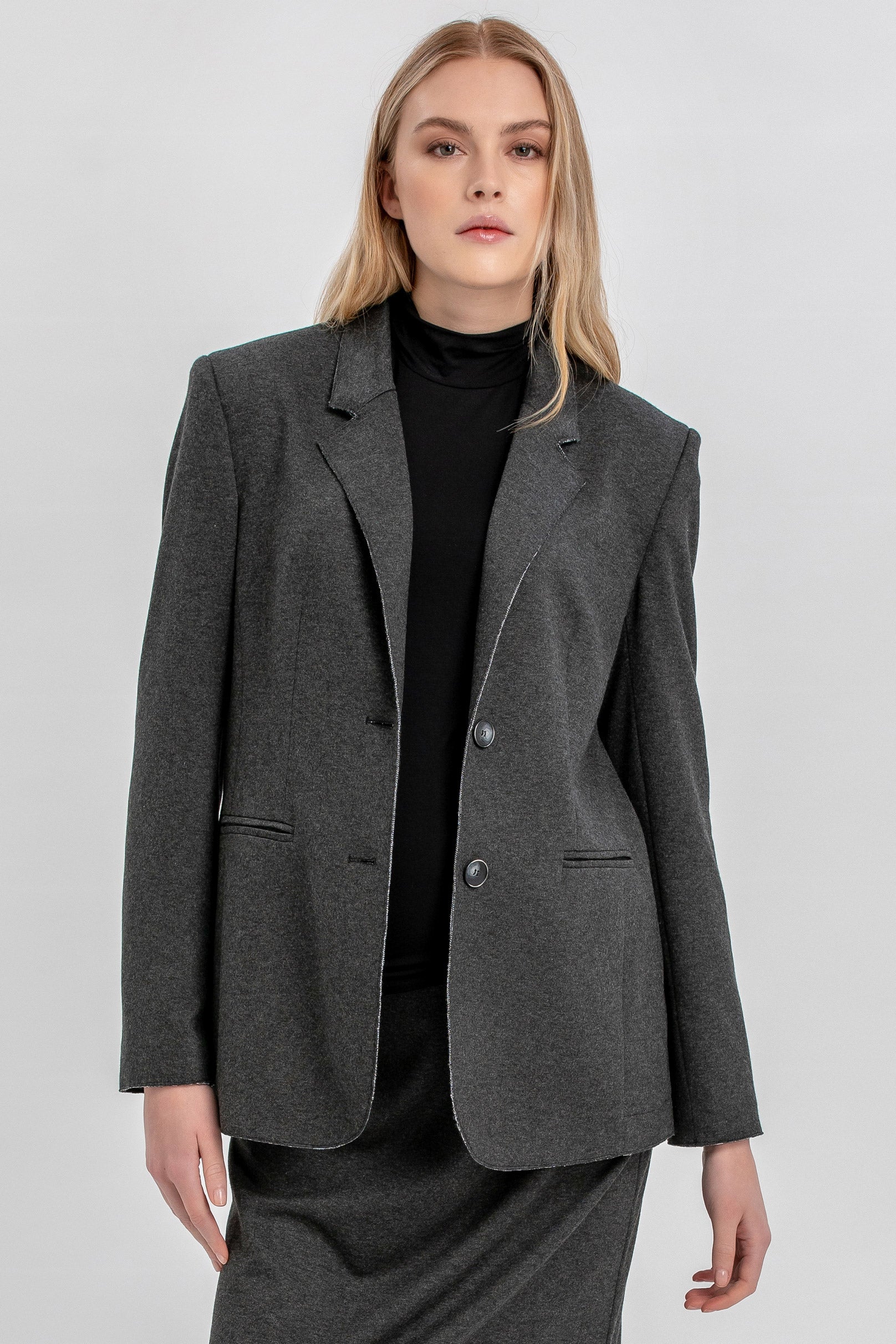 Donna in completo premaman giacca e gonna grigio scuro, fondo neutro, look elegante
