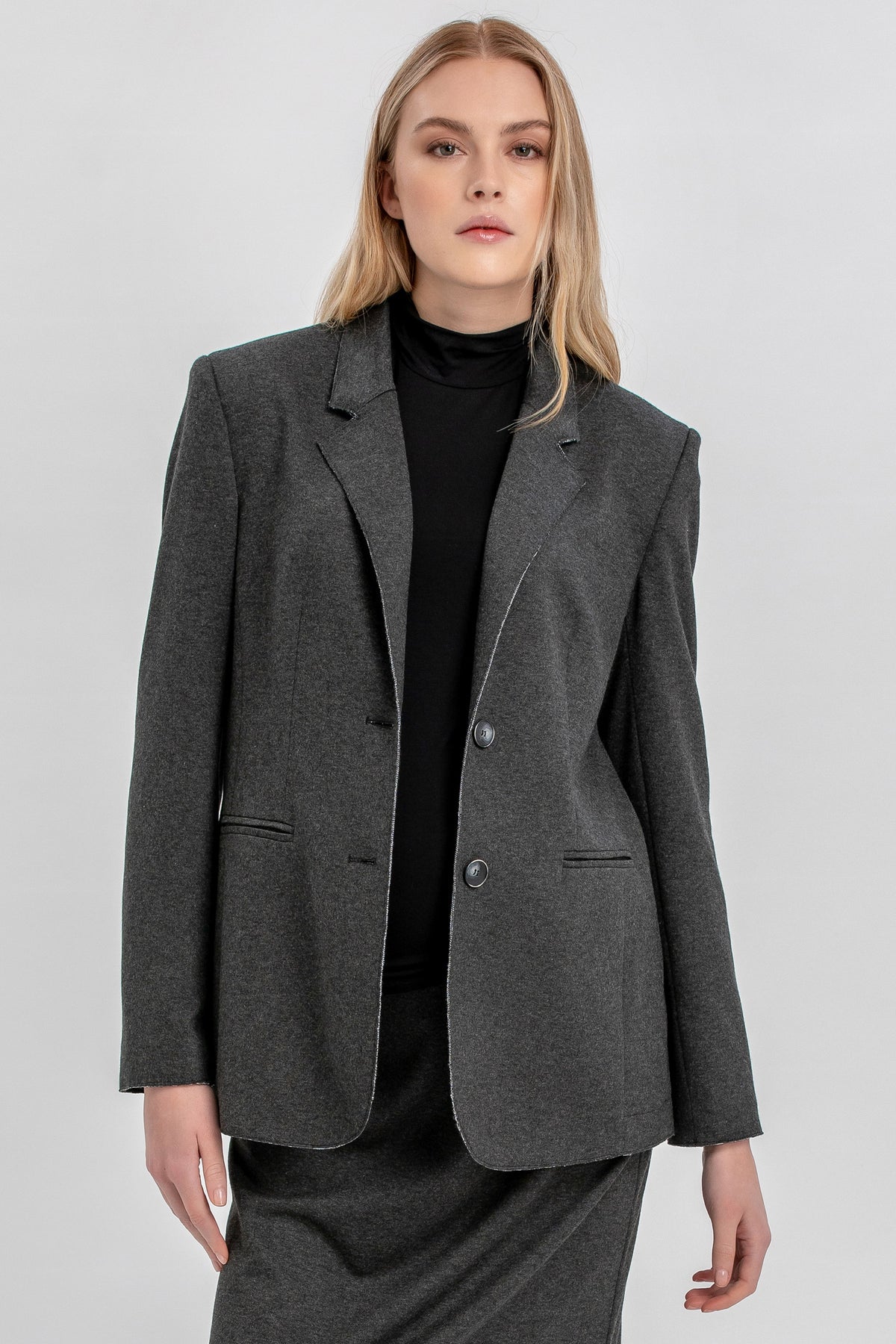 Donna in completo premaman giacca e gonna grigio scuro, fondo neutro, look elegante