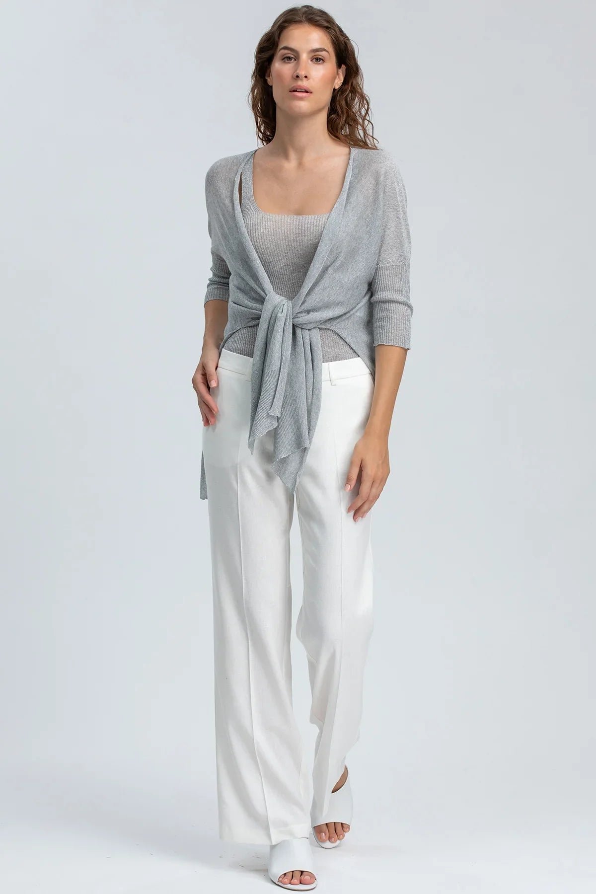 Modella indossa maglia e pantaloni bianchi premaman eleganti, look abbigliamento premaman.
