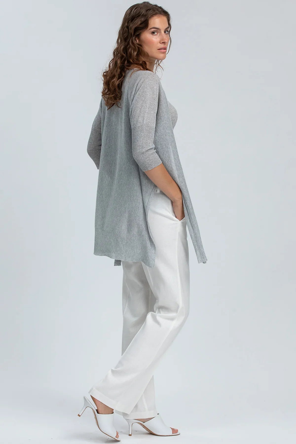 Donna che indossa cardigan premaman grigio e pantaloni bianchi eleganti