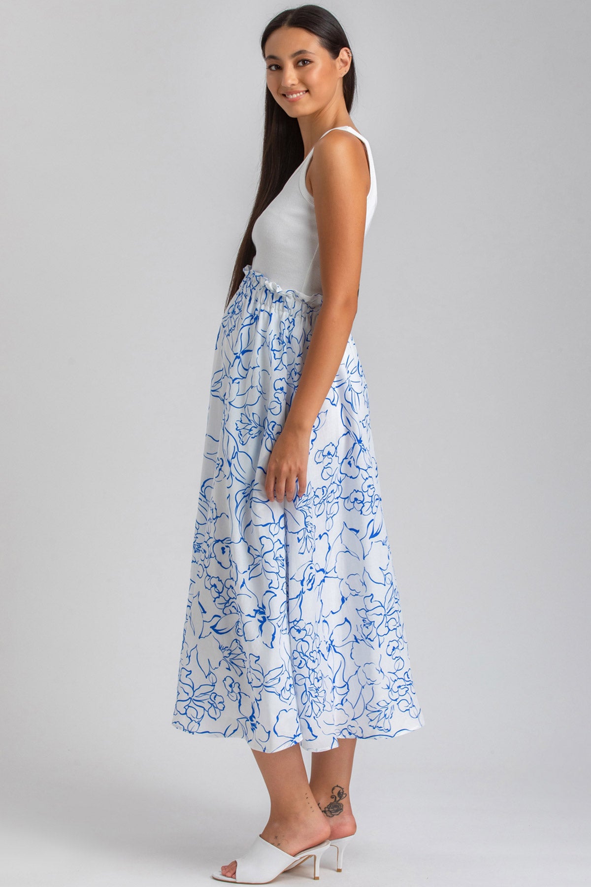 Donna incinta con abito premaman elegante bianco con fantasia floreale blu, su sfondo neutro