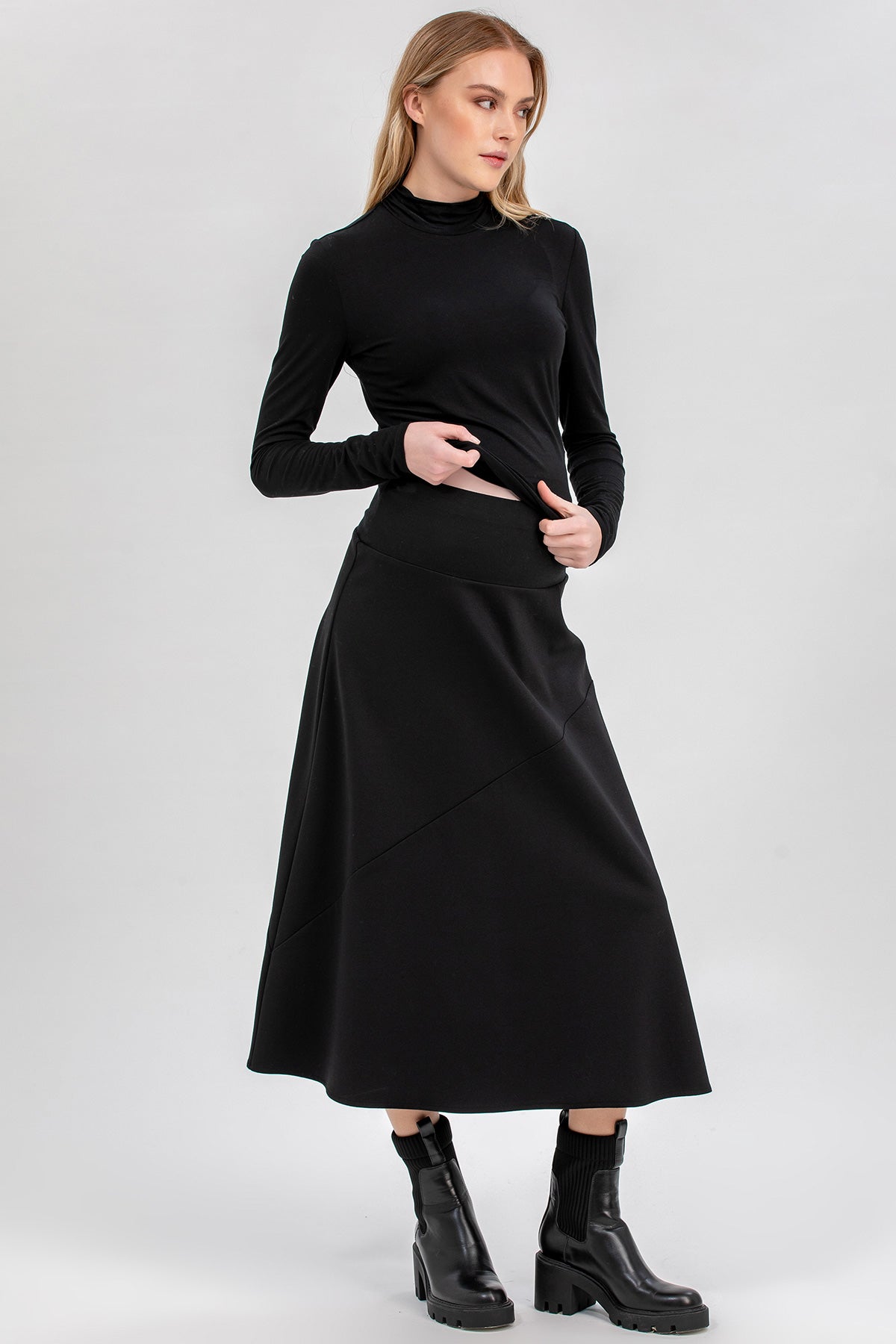 Donna con gonna premaman nera lunga e maglia a maniche lunghe, look elegante gravidanza