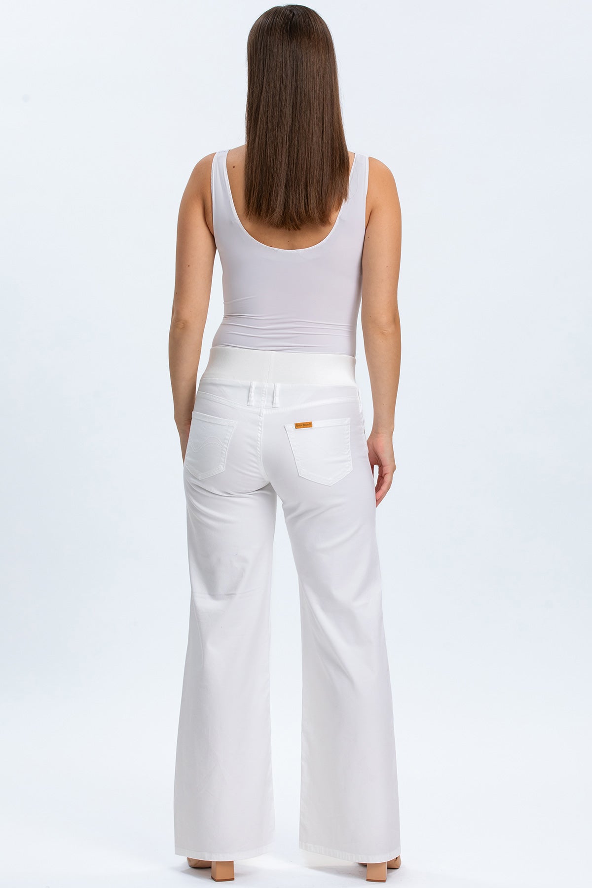 Pantaloni premaman bianchi a zampa con fascia elasticizzata in vita, indossati da donna di spalle