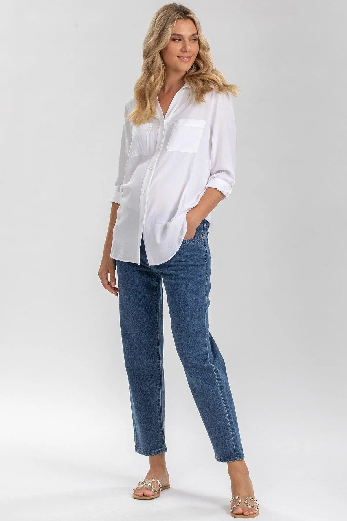 Donna incinta con camicia bianca premaman e jeans blu, abbigliamento maternità elegante