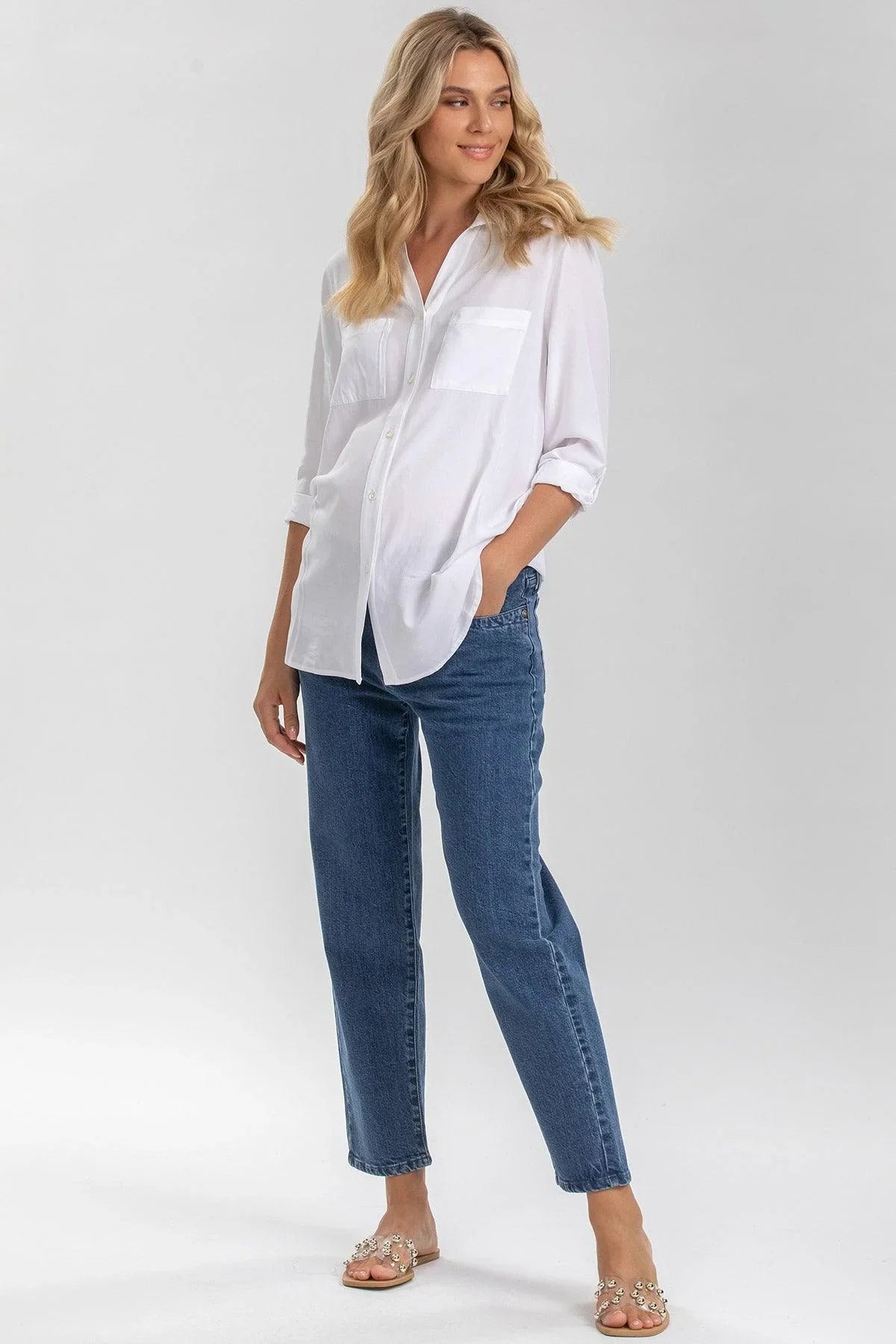 Donna incinta con camicia bianca premaman e jeans blu, abbigliamento maternità elegante