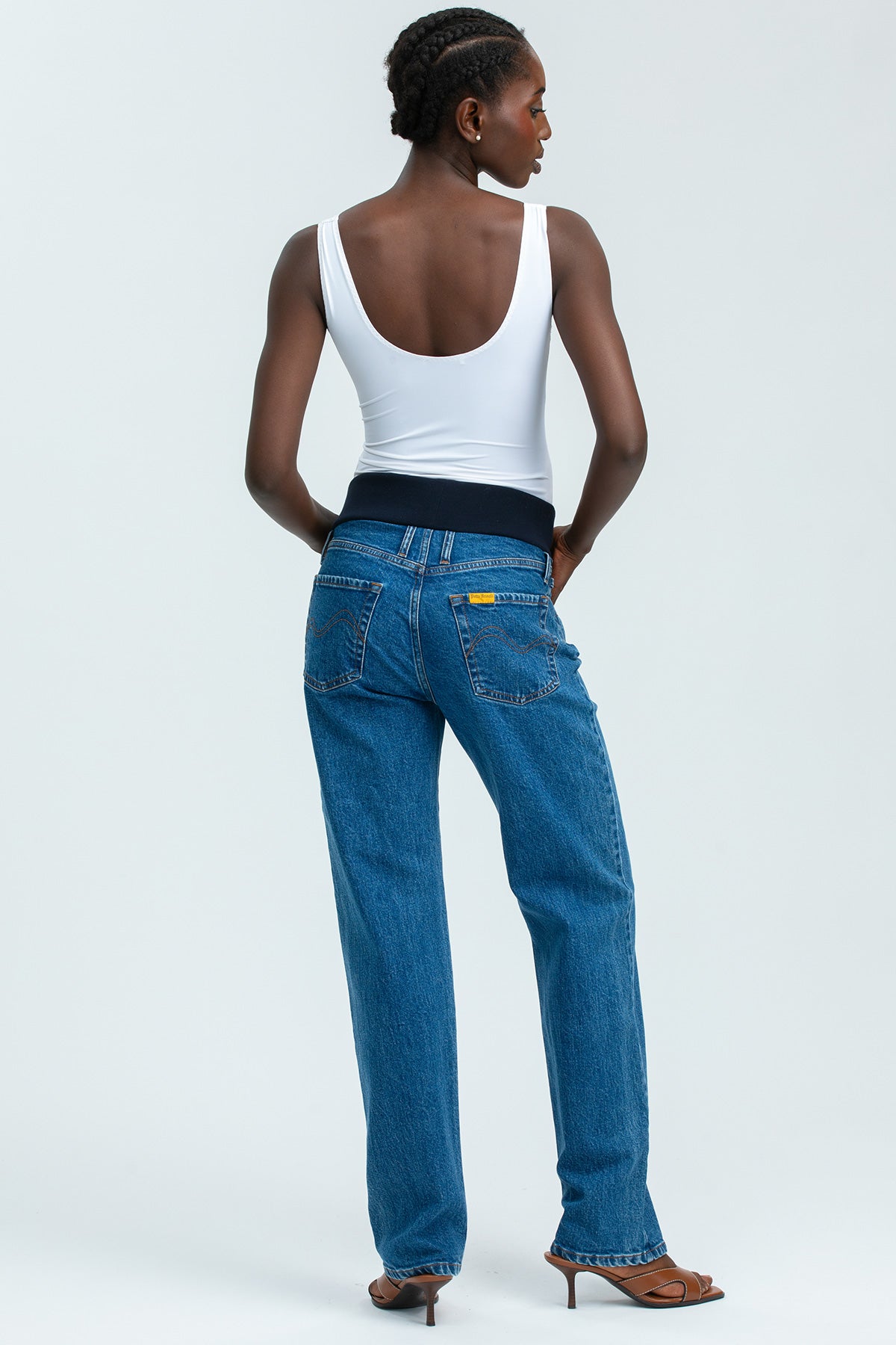 Model wearing high-waisted straight-leg maternity jeans with a comfortable stretchy belly band, styled for an elegant maternity look.