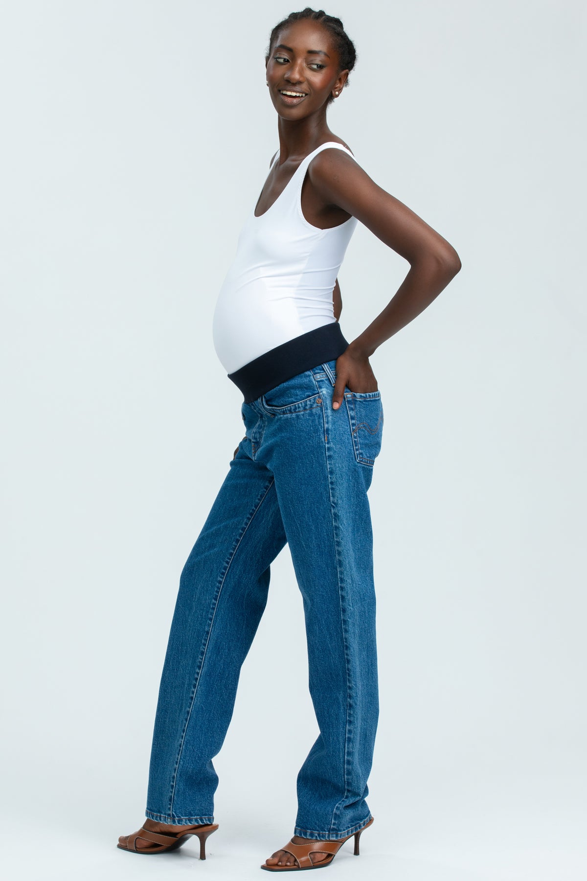 Modella indossa jeans premaman dritti a vita alta con fascia elastica comoda, abbigliamento premaman elegante.