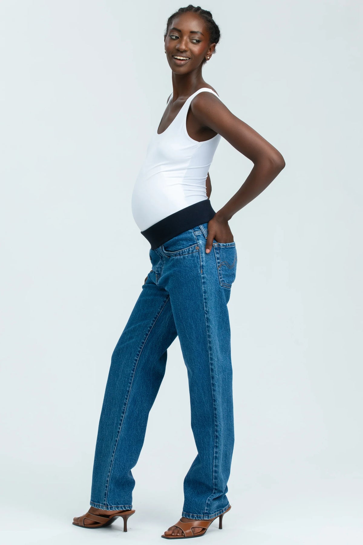 Modella indossa jeans premaman dritti a vita alta con fascia elastica comoda, abbigliamento premaman elegante.