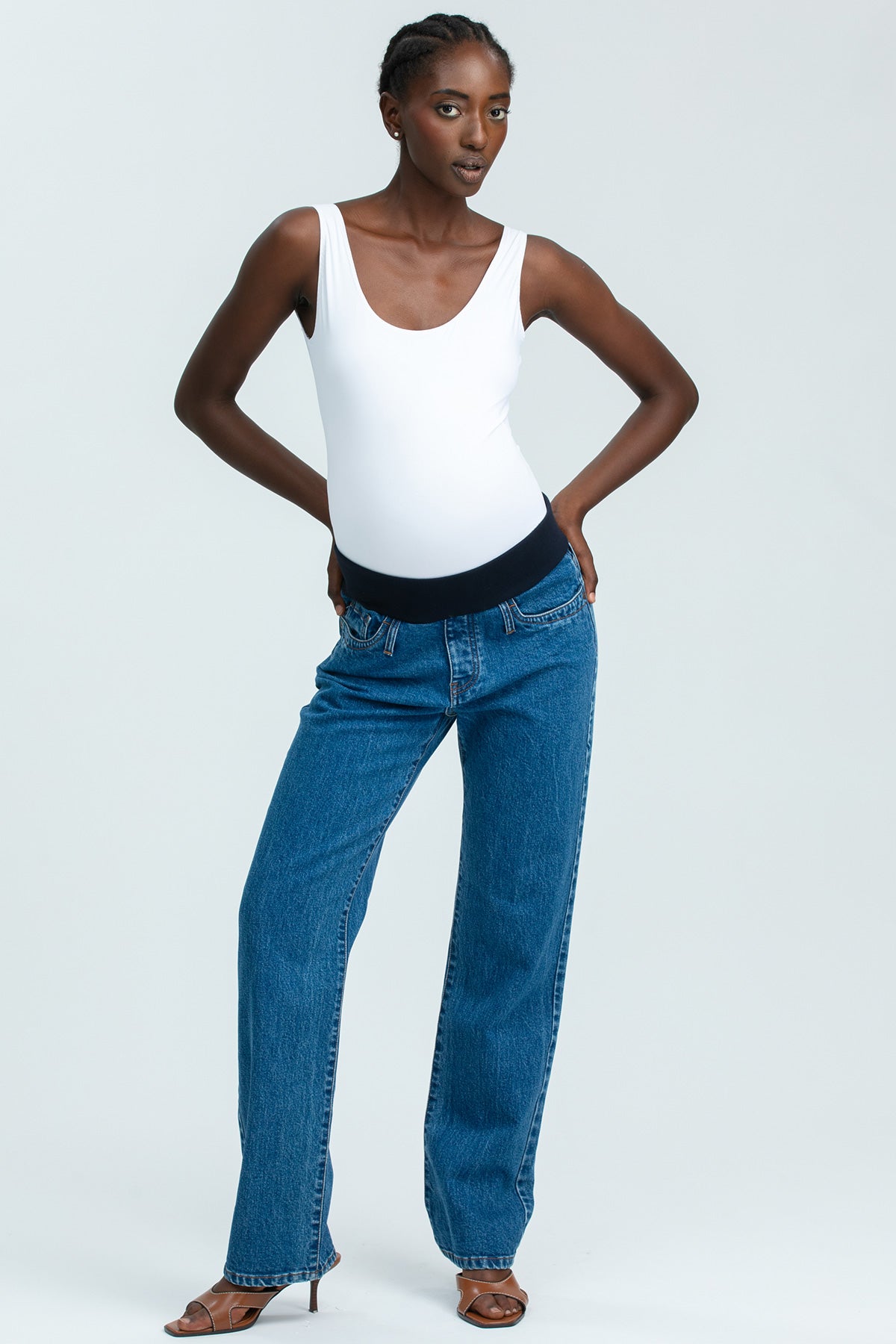 Modella indossa jeans premaman dritti a vita alta con fascia elastica comoda, abbigliamento premaman elegante.