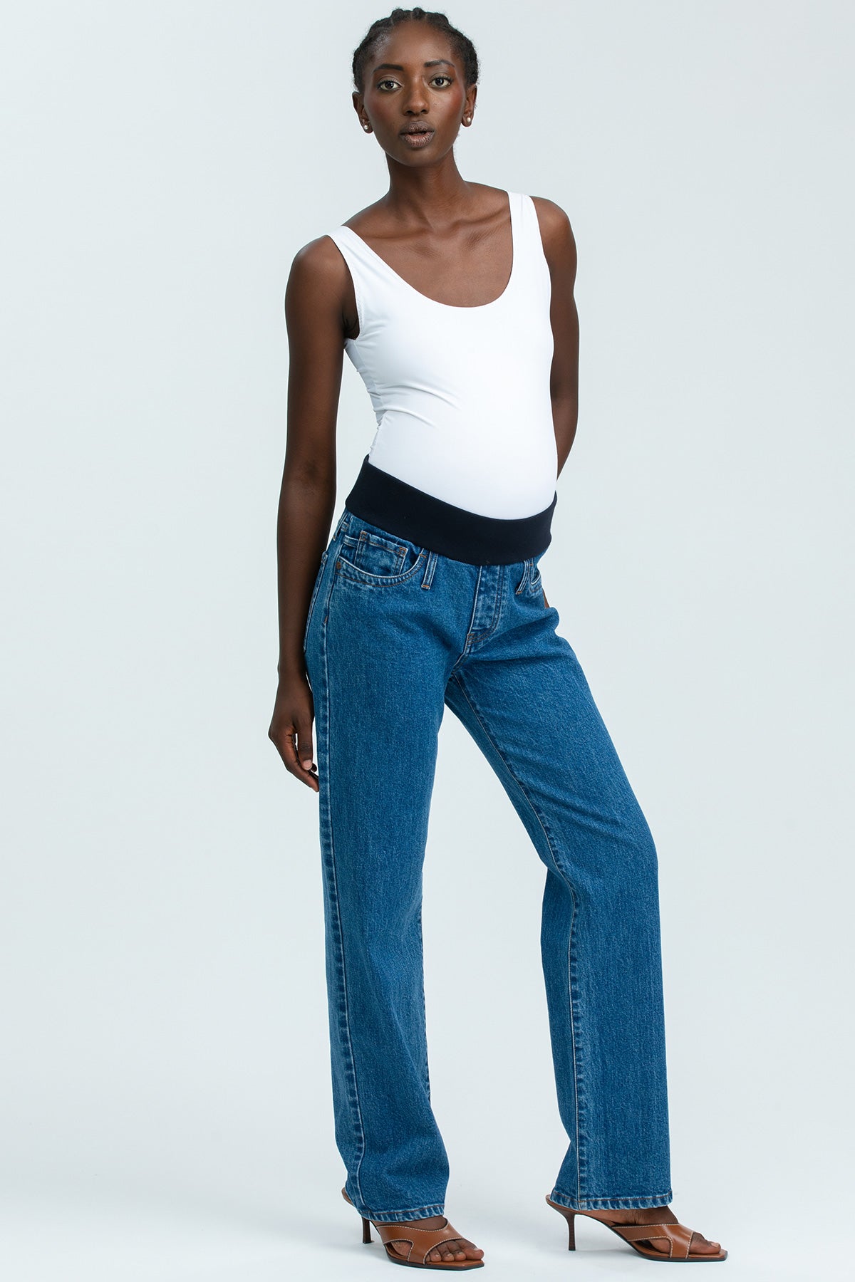 Model wearing high-waisted straight-leg maternity jeans with a comfortable stretchy belly band, styled for an elegant maternity look.