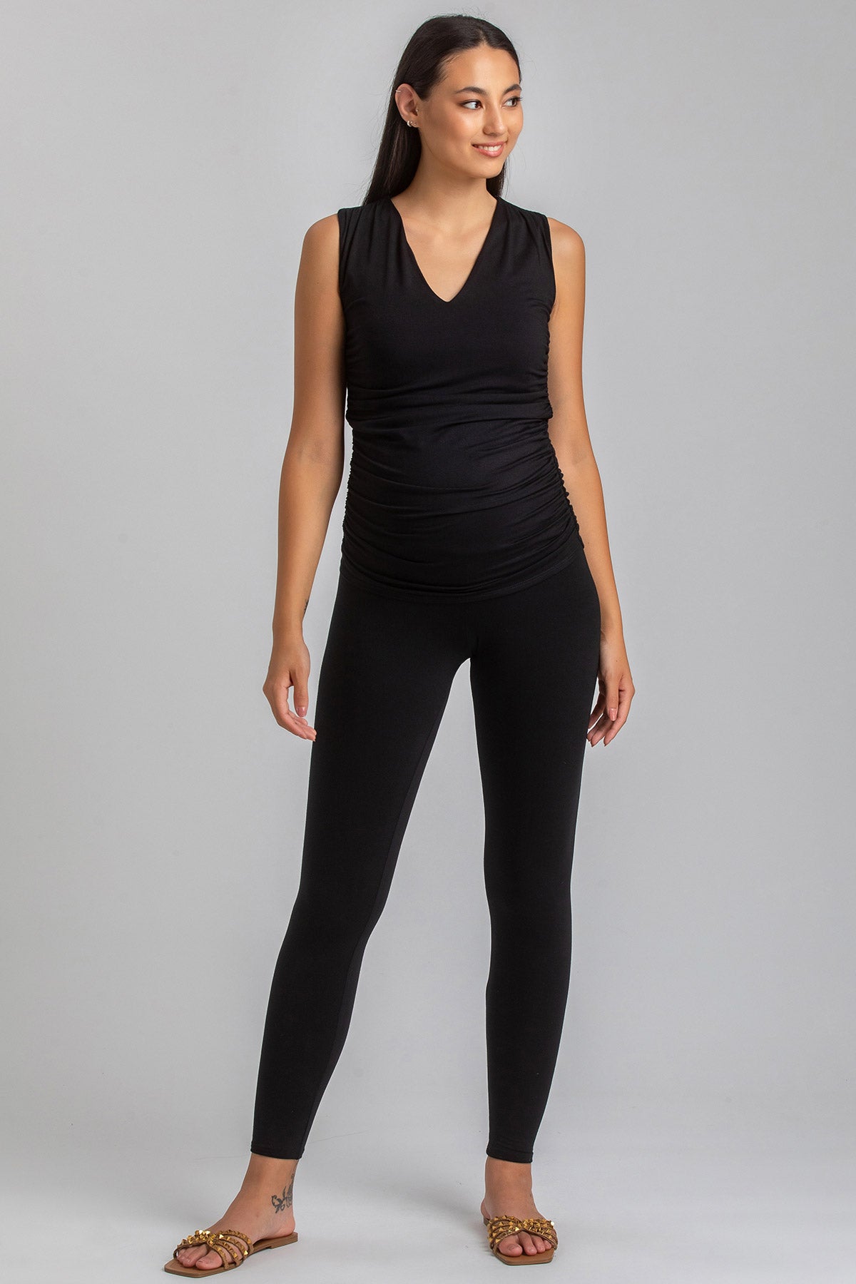 Donna incinta con top premaman smanicato nero e leggings, abbigliamento premaman elegante