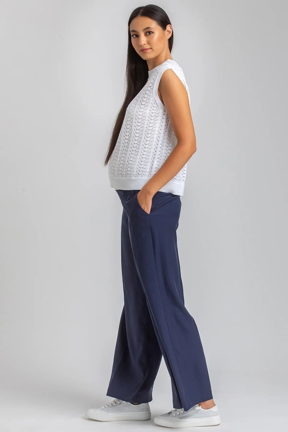 Modella indossa top premaman bianco senza maniche e pantaloni premaman blu larghi