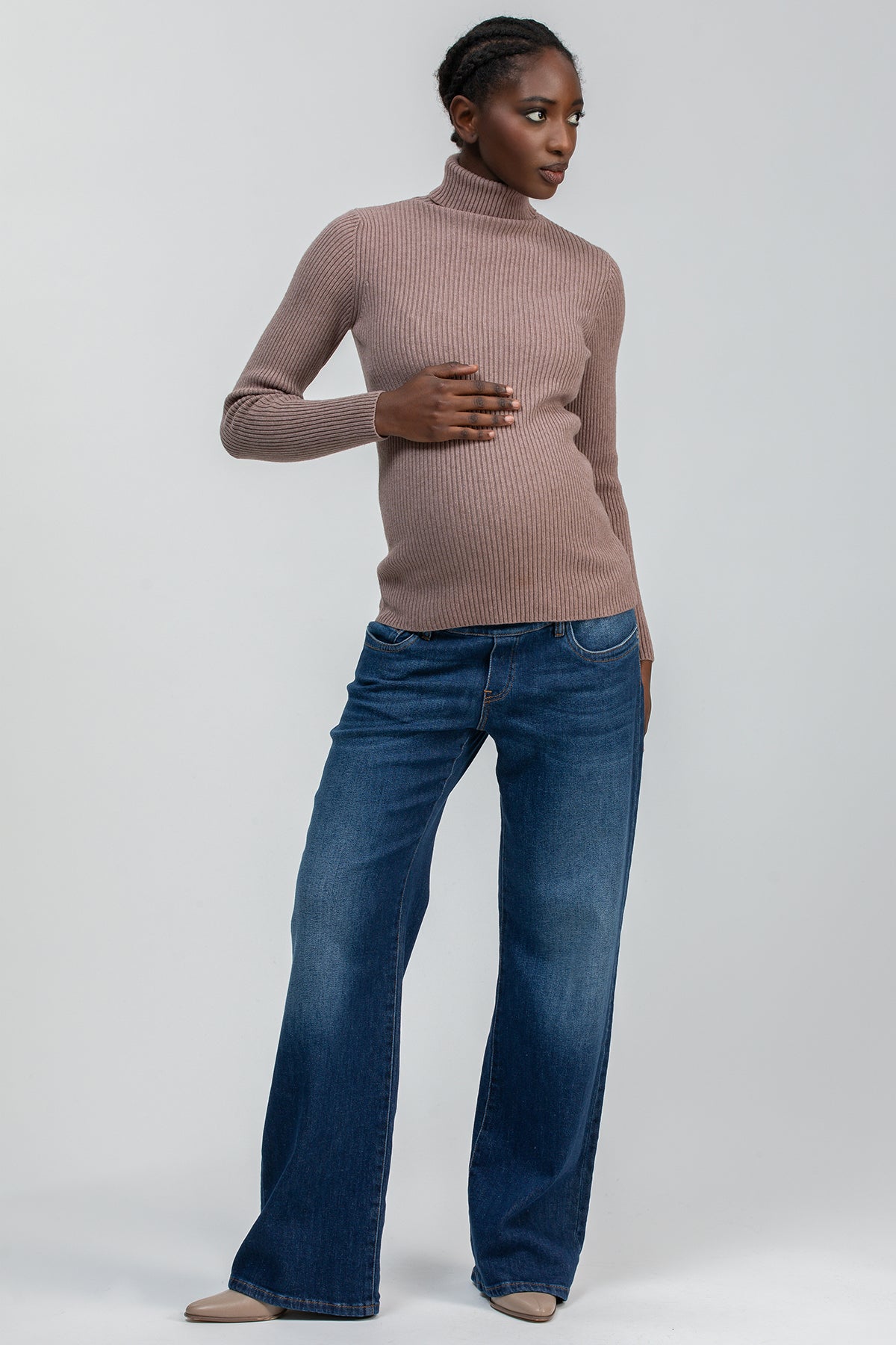 Donna incinta con maglione premaman a collo alto marrone e jeans confortevoli