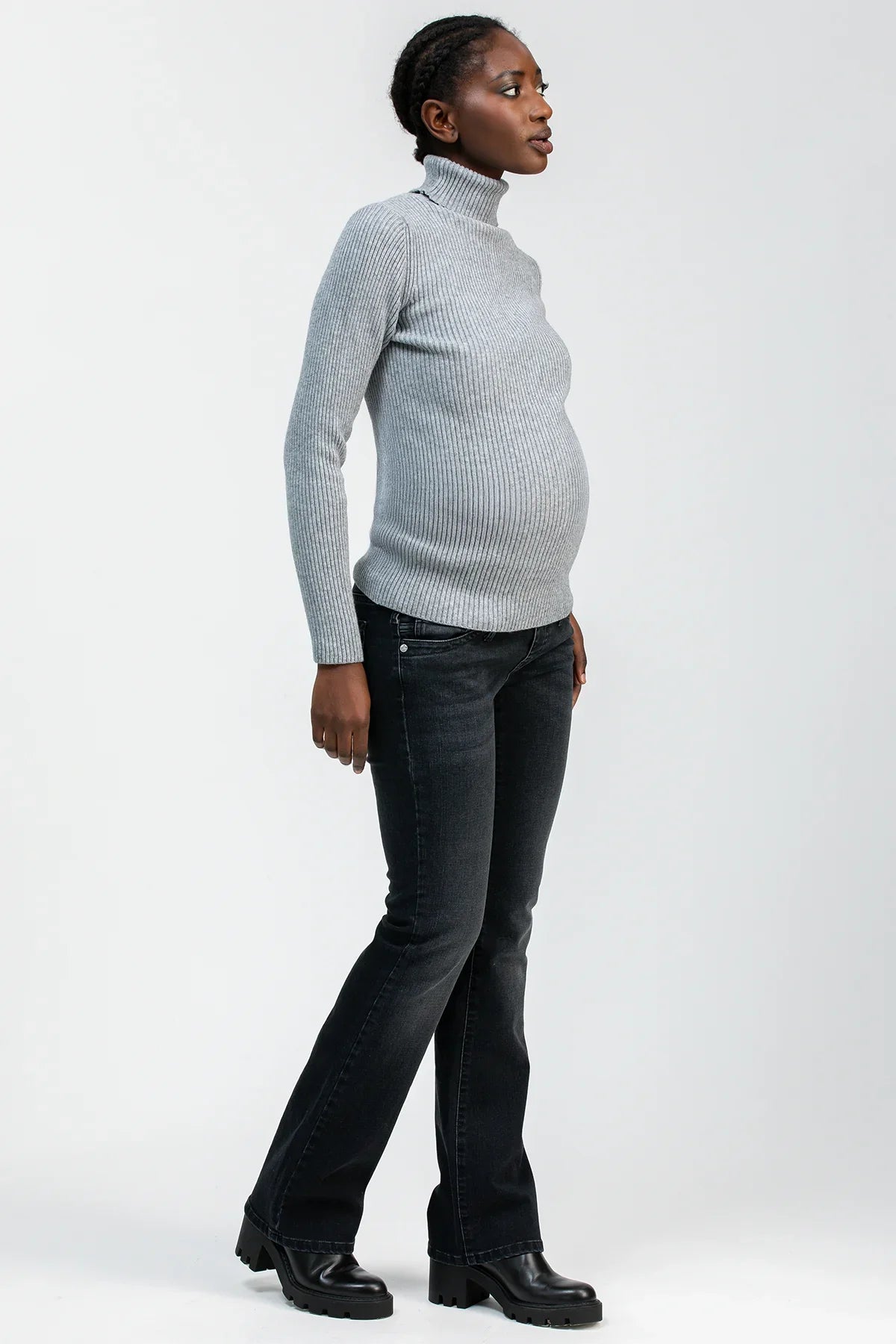 Donna incinta con maglione grigio e jeans premaman bootcut neri in posa laterale