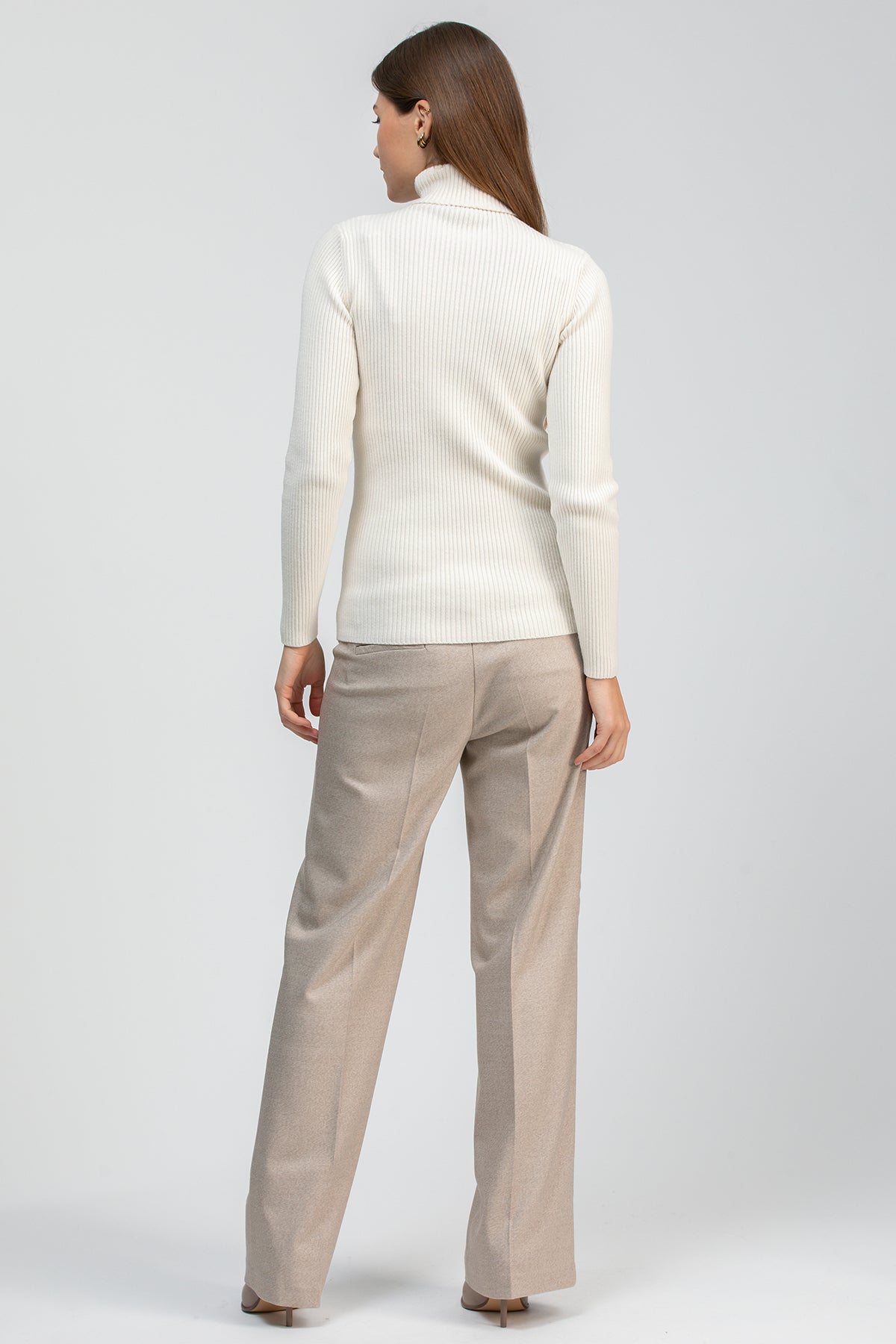 Look premaman elegante con maglia panna a collo alto e pantaloni beige dal taglio sartoriale